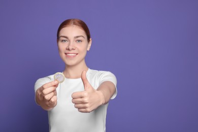 Photo of Woman with condom showing thumb up on purple background, space for text. Safe sex