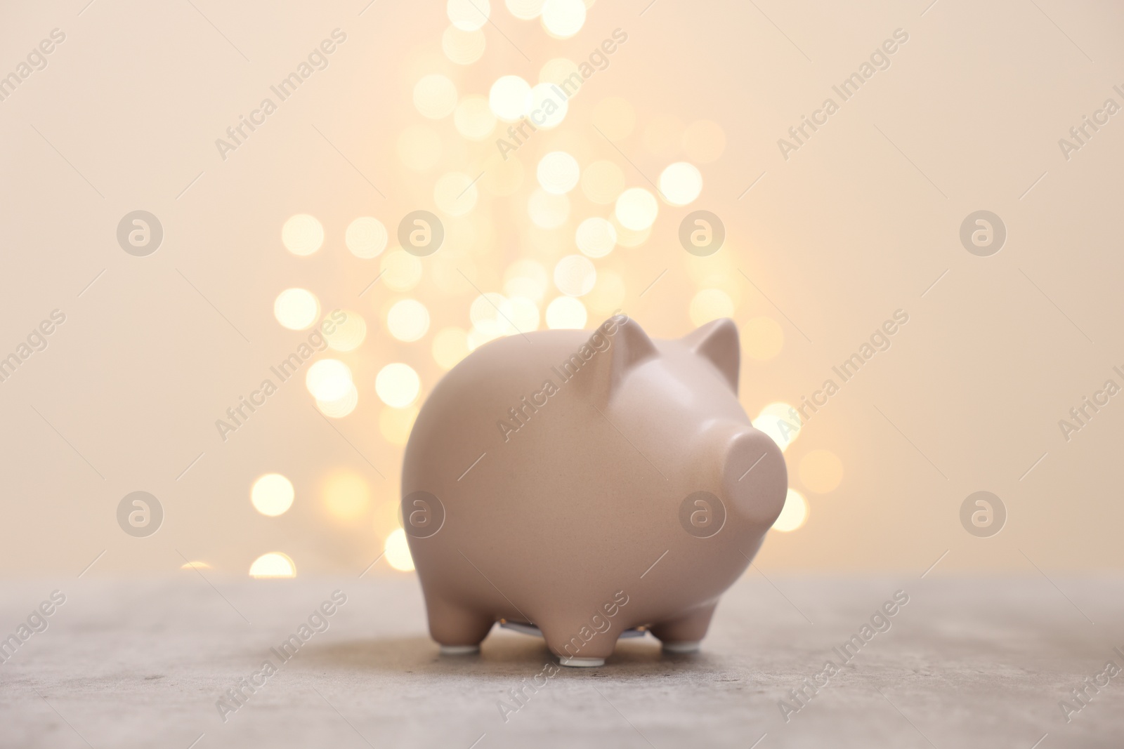 Photo of Piggy bank on grey table against blurred lights