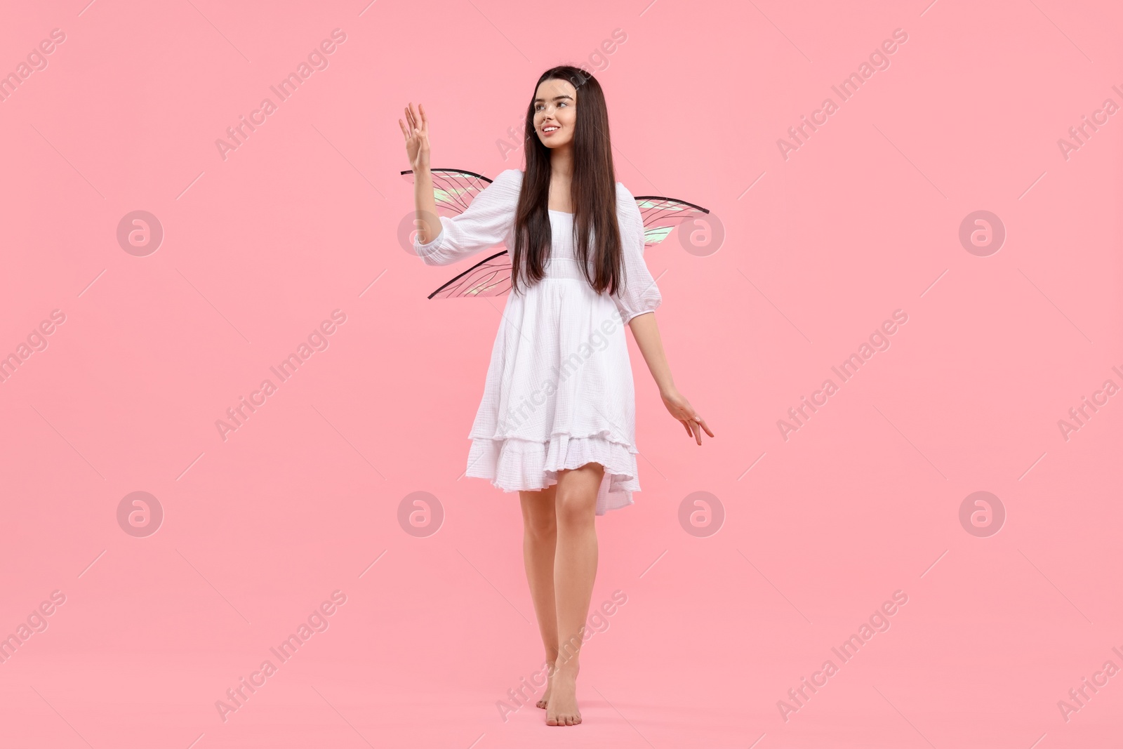 Photo of Beautiful girl in fairy costume with wings on pink background