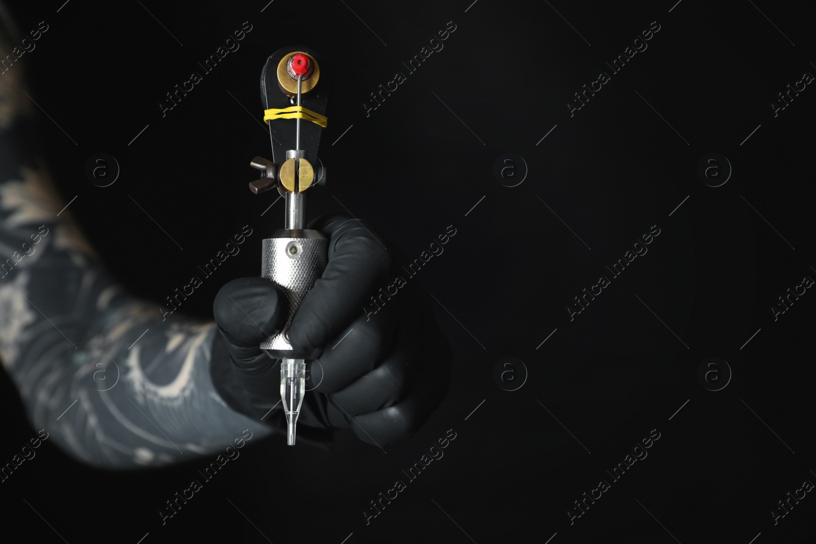 Photo of Artist with professional tattoo machine on black background, closeup. Space for text