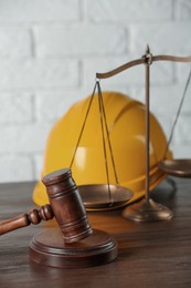 Photo of Labour, construction and land law concepts. Judge gavel, scales of justice with protective helmet on wooden table