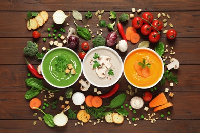 Photo of Various cream soups and ingredients on wooden background, flat lay. Healthy food