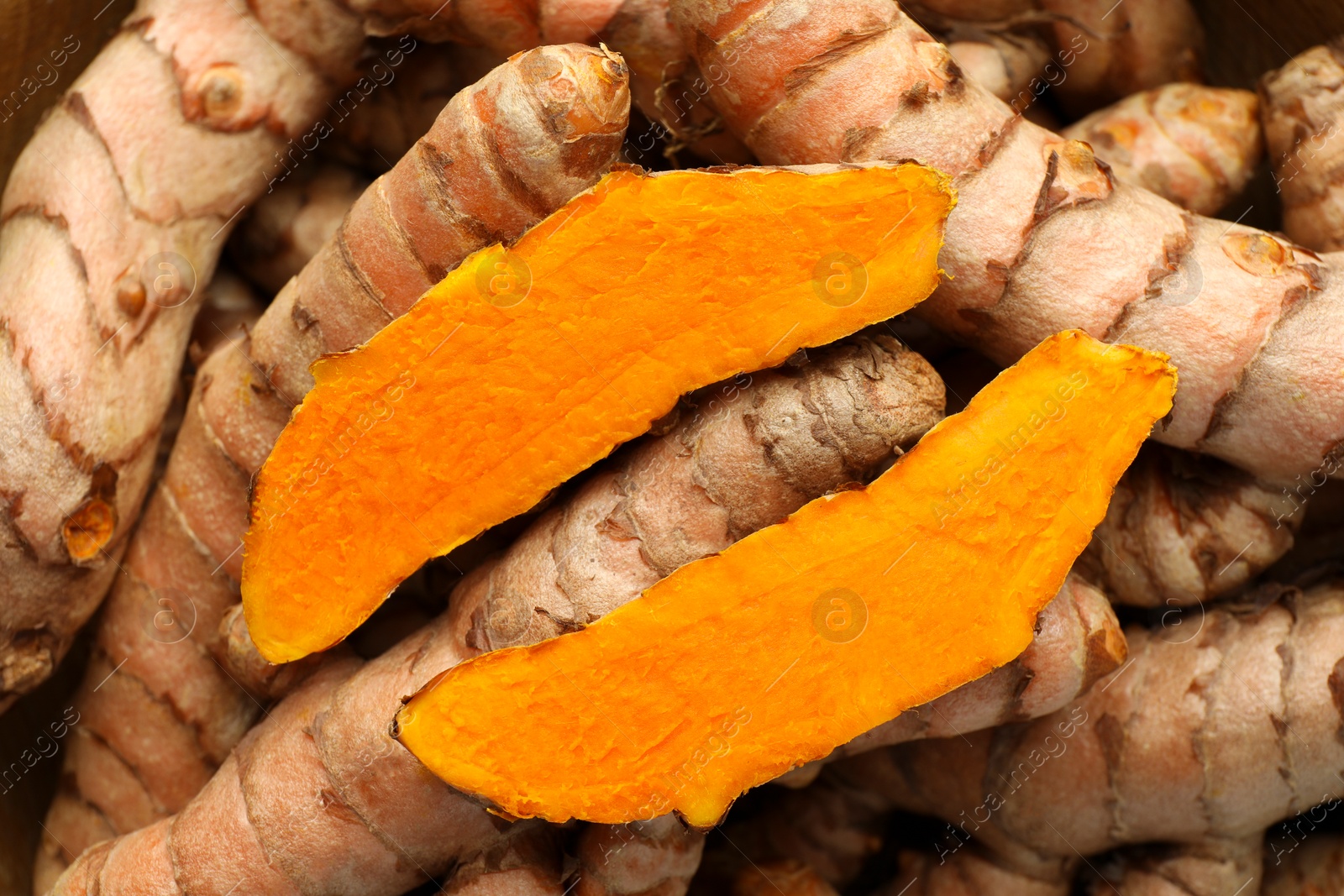 Photo of Whole and cut turmeric roots as background, top view