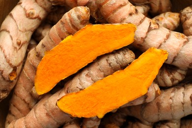 Photo of Whole and cut turmeric roots as background, top view