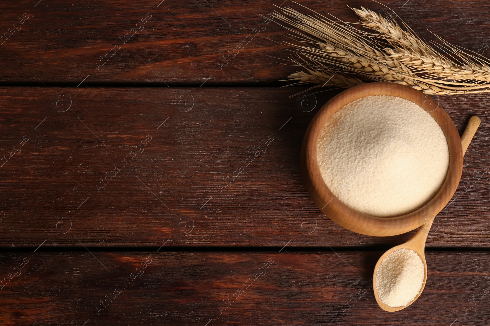 Photo of Semolina and spikelets on wooden table, flat lay. Space for text