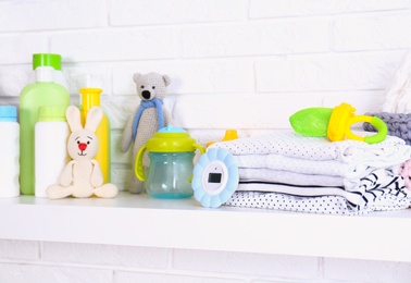 Baby accessories on shelf near white brick wall