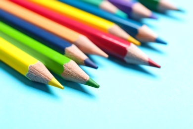 Photo of Colorful pencils on light blue background, closeup
