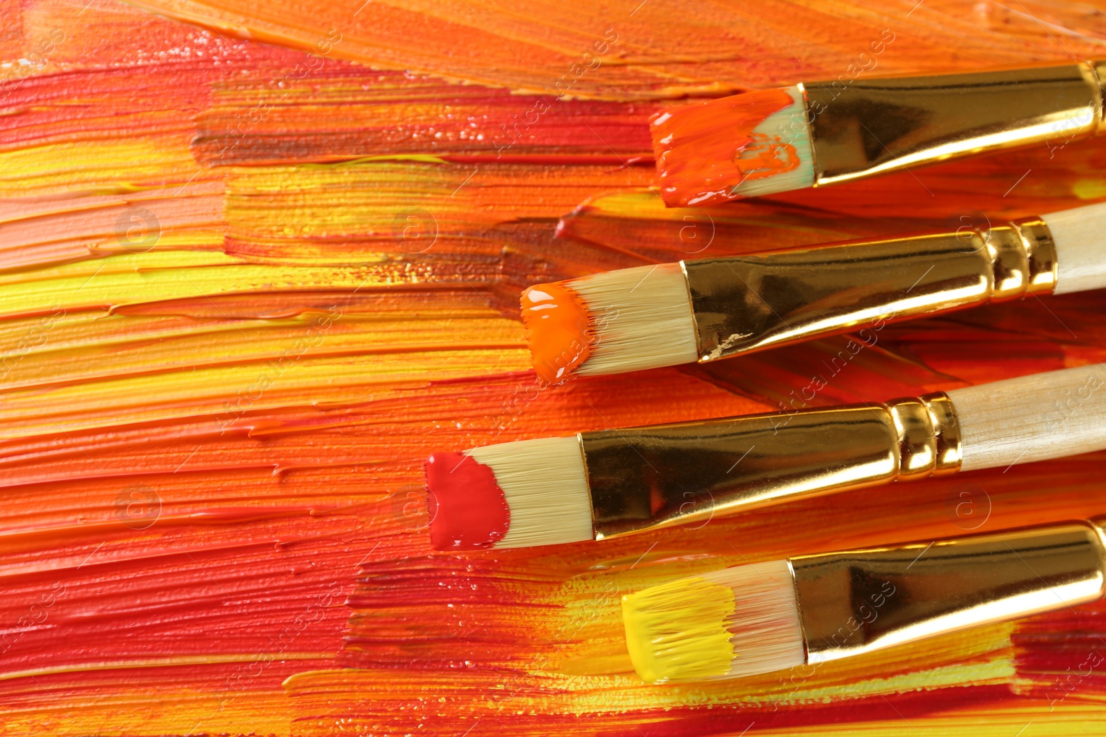 Photo of Set of different brushes on abstract colorful paint, top view