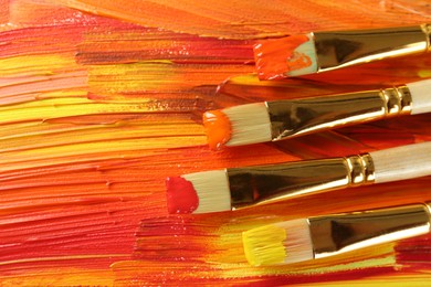 Set of different brushes on abstract colorful paint, top view