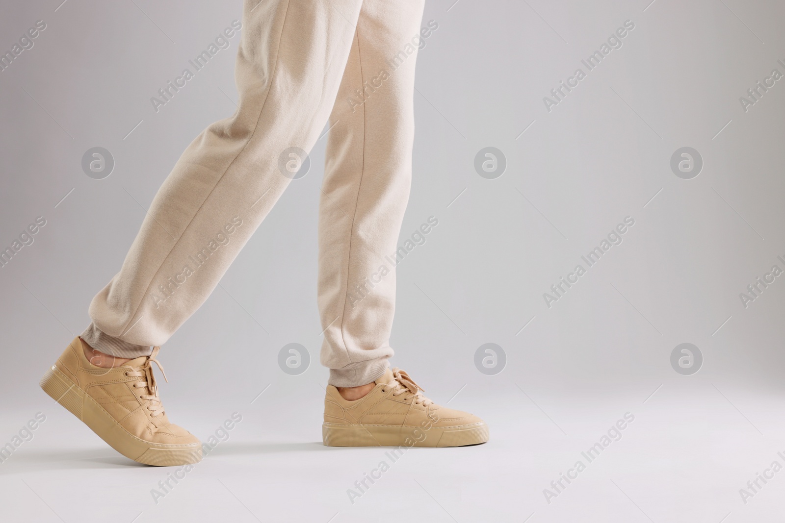 Photo of Man walking in sneakers on light grey background, closeup. Space for text