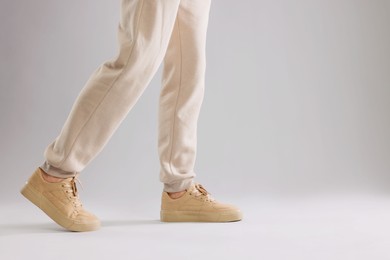 Photo of Man walking in sneakers on light grey background, closeup. Space for text
