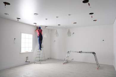 Photo of Worker installing stretch ceiling in empty room