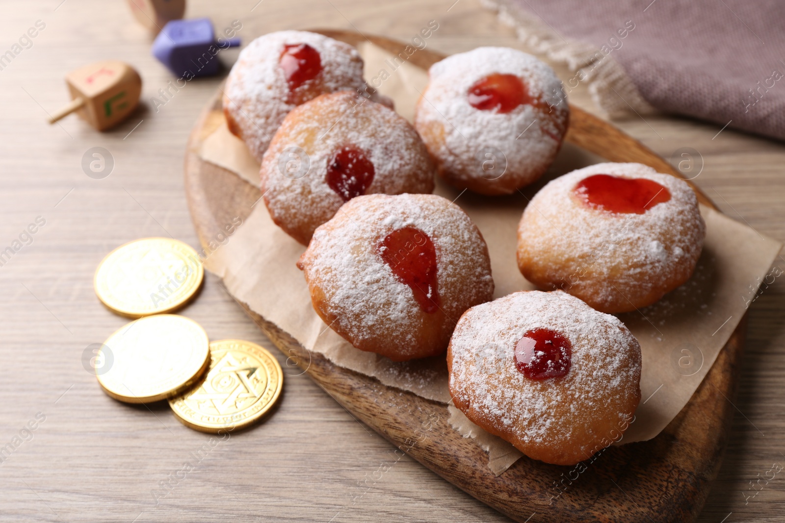 Photo of Hanukkah donuts, dreidels and coins on wooden table