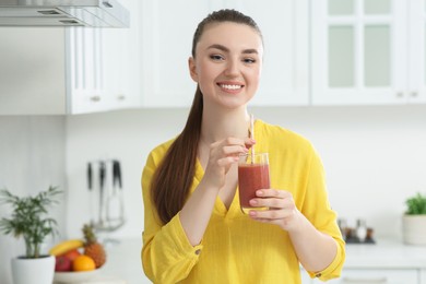 Photo of Beautiful young woman with delicious smoothie in kitchen