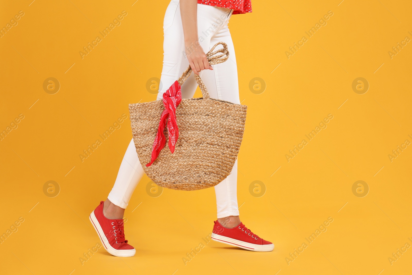 Photo of Young woman with stylish straw bag on yellow background, closeup. Space for text