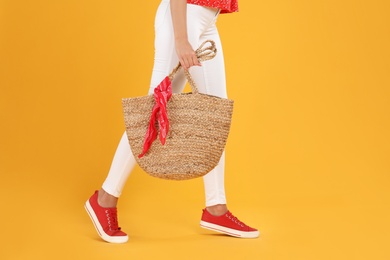 Young woman with stylish straw bag on yellow background, closeup. Space for text