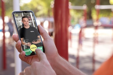 Image of Man having workout with personal trainer via smartphone outdoors, closeup