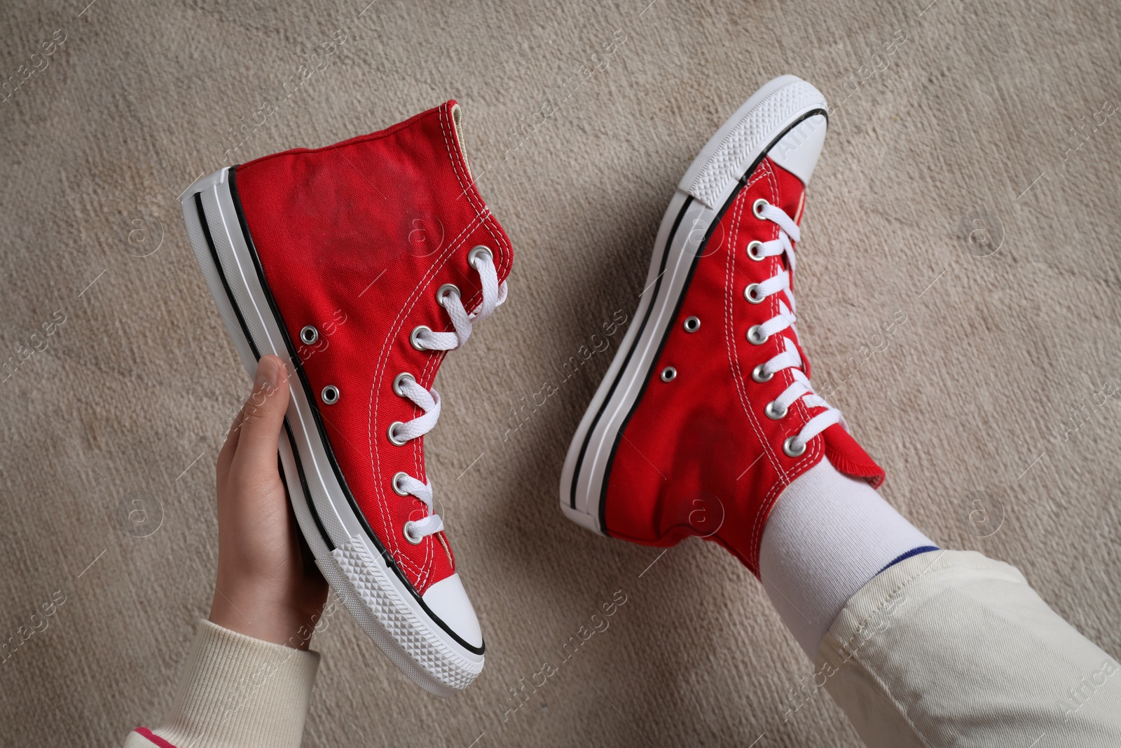 Photo of Woman with new stylish red sneakers sitting on beige carpet, top view