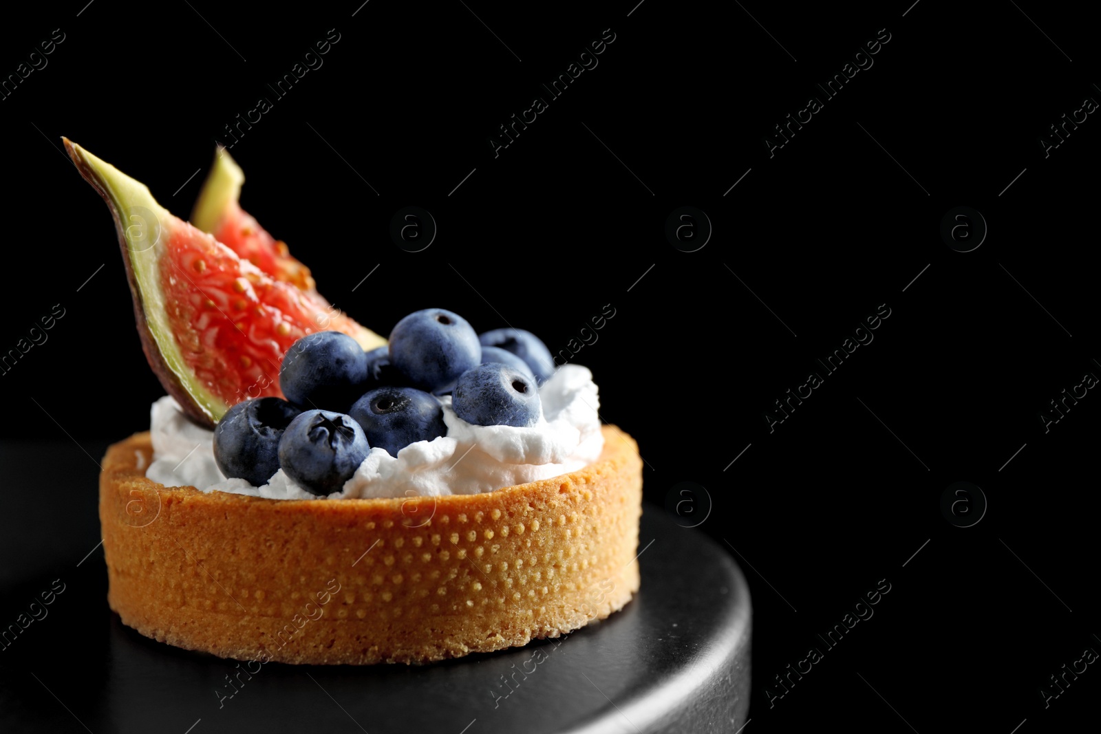 Photo of Tart with blueberries and figs on black table against dark background, space for text. Delicious pastries