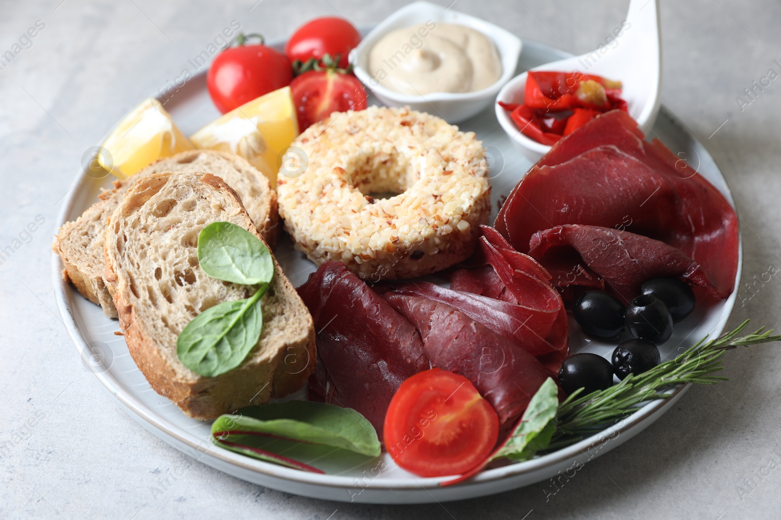 Photo of Delicious bresaola and other ingredients for sandwich on light grey table, closeup