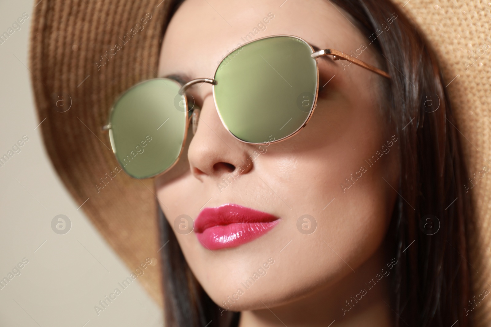 Photo of Beautiful woman in stylish sunglasses and hat on beige background