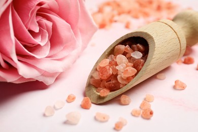 Aromatic sea salt and beautiful rose on pink marble table, closeup