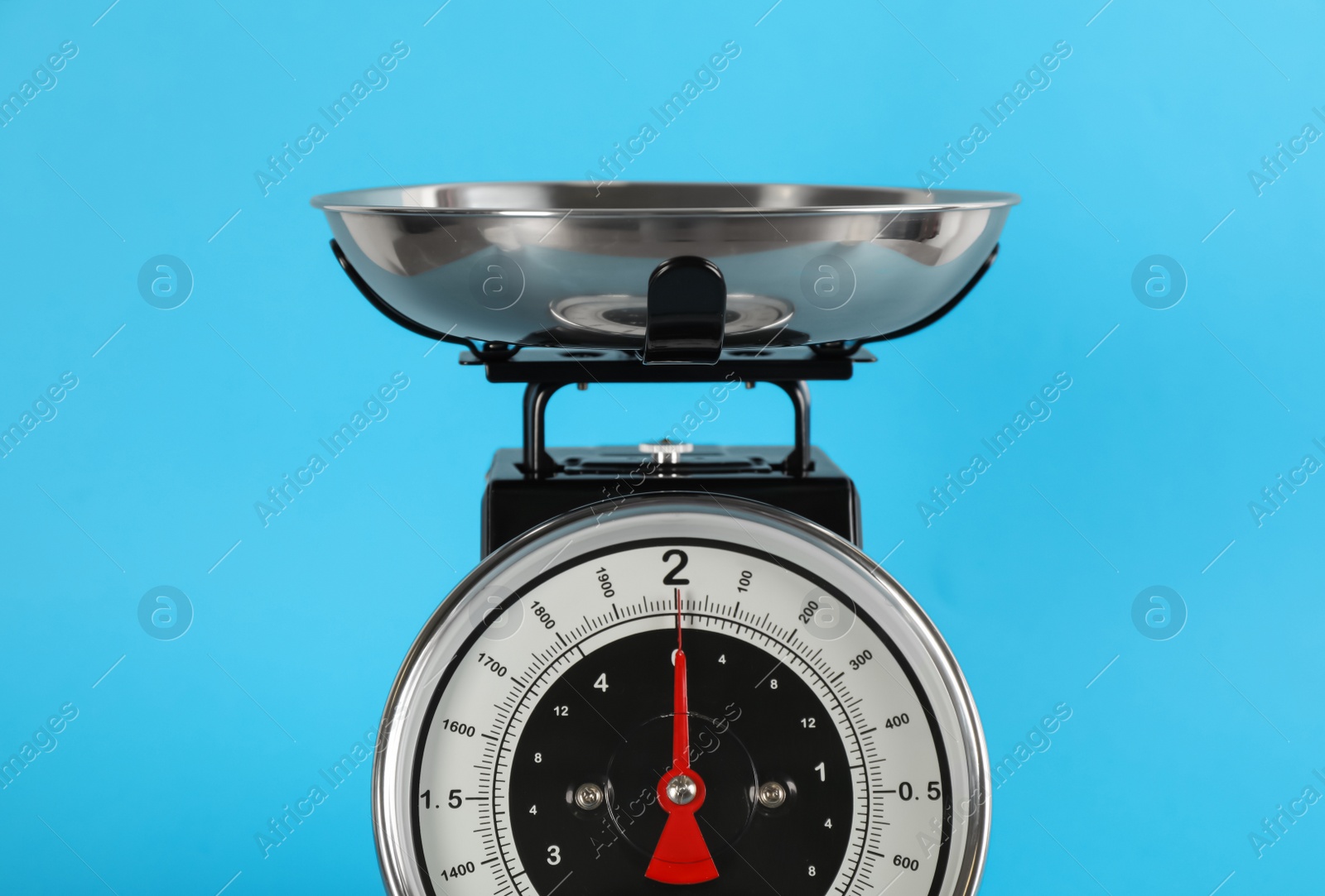 Photo of Retro mechanical kitchen scale on light blue background, closeup