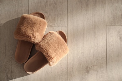 Photo of Brown fuzzy slippers on floor indoors, flat lay. Space for text