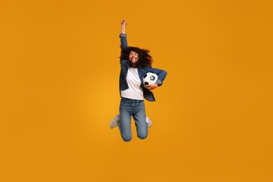 Happy fan with soccer ball jumping on yellow background