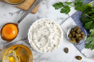 Photo of Tasty tartar sauce and ingredients on white marble table, flat lay