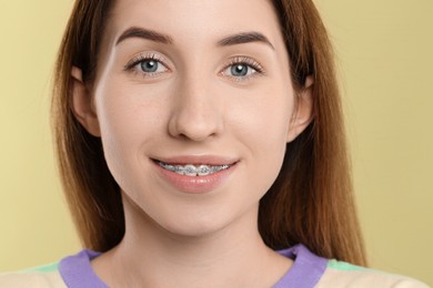 Photo of Portrait of smiling woman with dental braces on light green background, closeup