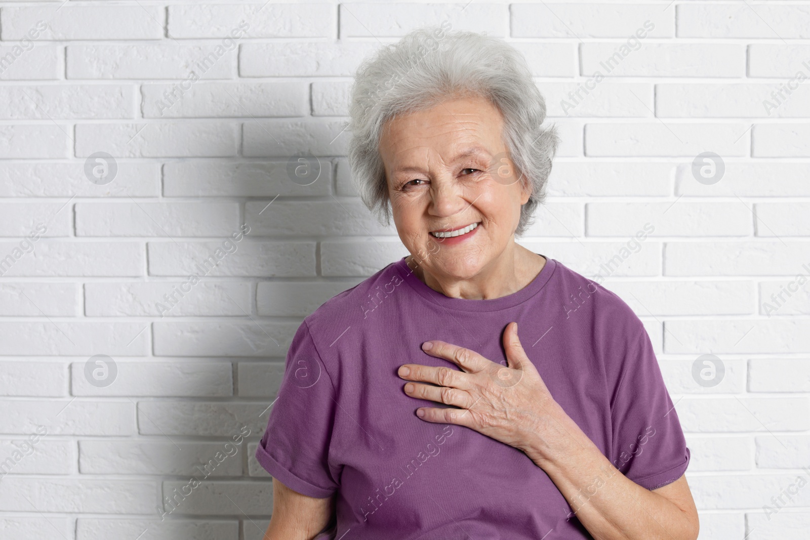 Photo of Portrait of mature woman near brick wall. Space for text