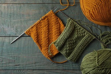 Soft yarns, knitting and metal needles on light blue wooden table, flat lay