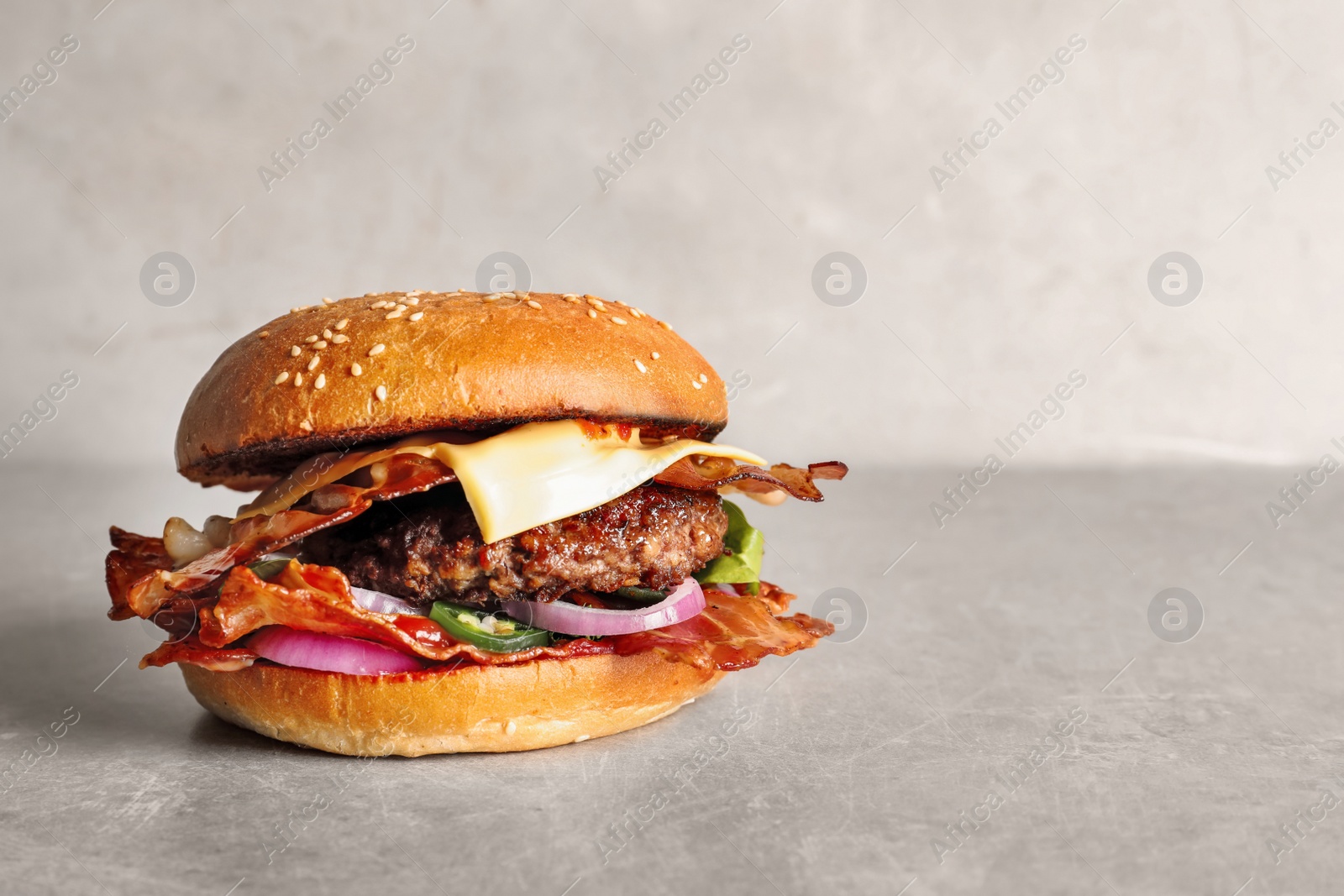 Photo of Tasty burger with bacon on table