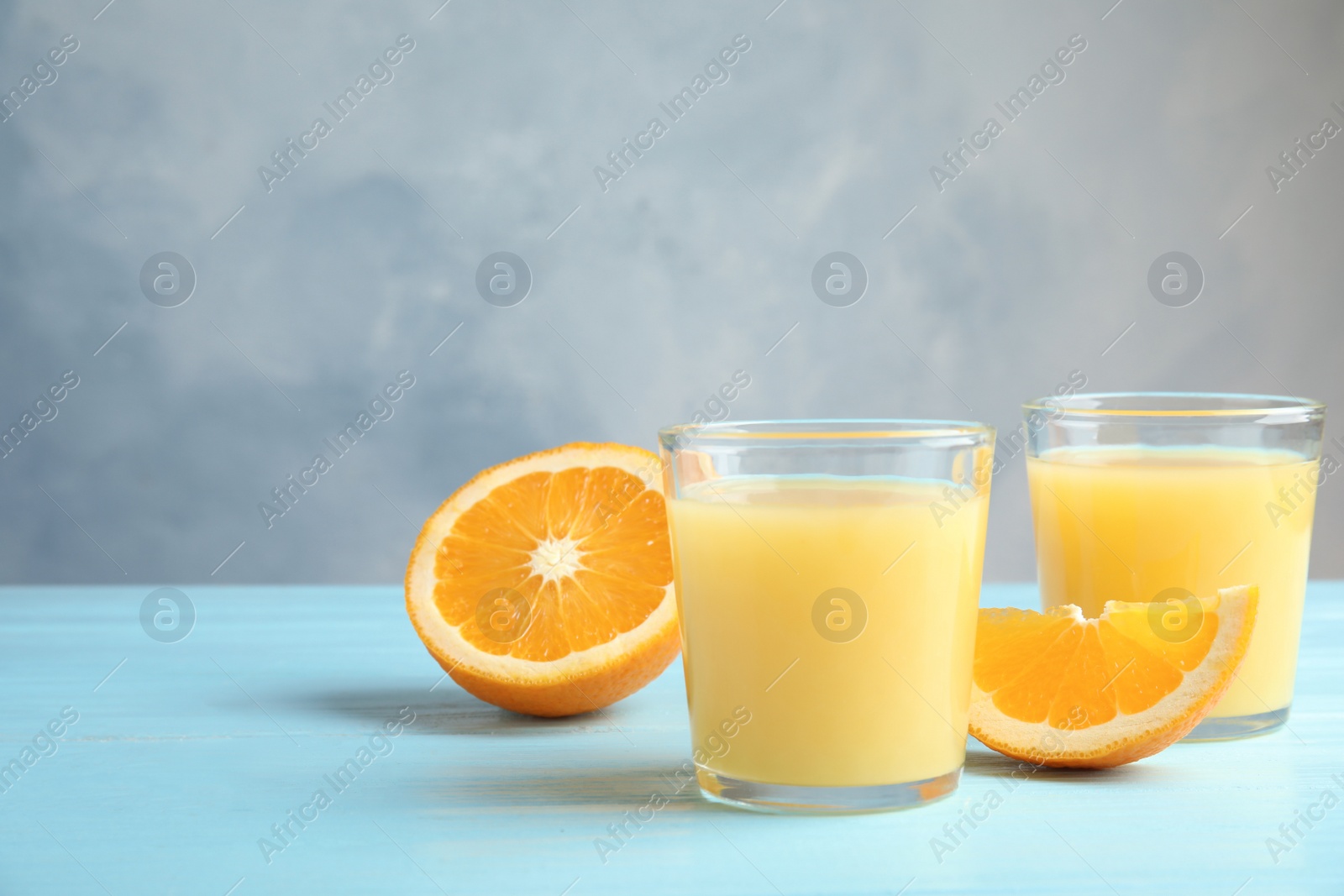 Photo of Glasses with orange juice and cut fruit on table, space for text