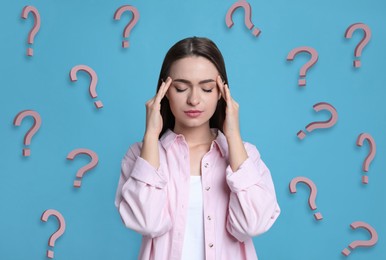 Image of Amnesia. Confused young woman and question marks on light blue background