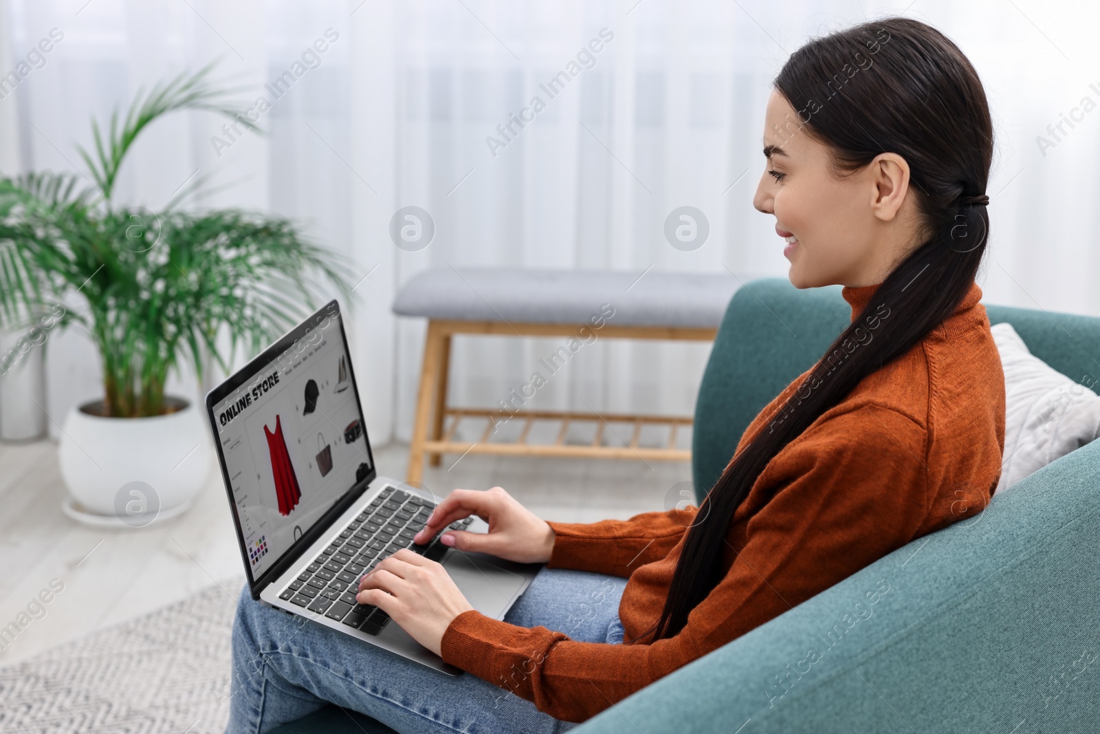 Photo of Beautiful young woman with laptop shopping online on sofa at home