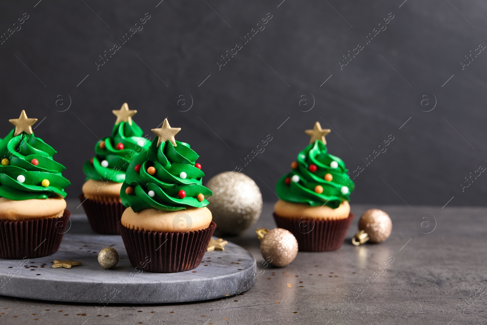 Photo of Christmas tree shaped cupcakes on grey table