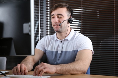 Male technical support operator with headset at workplace