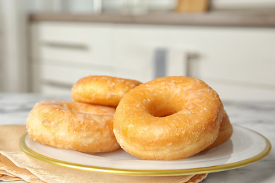 Photo of Delicious glazed donuts on marble table, closeup