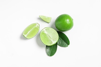 Fresh ripe limes and leaves on white background, flat lay