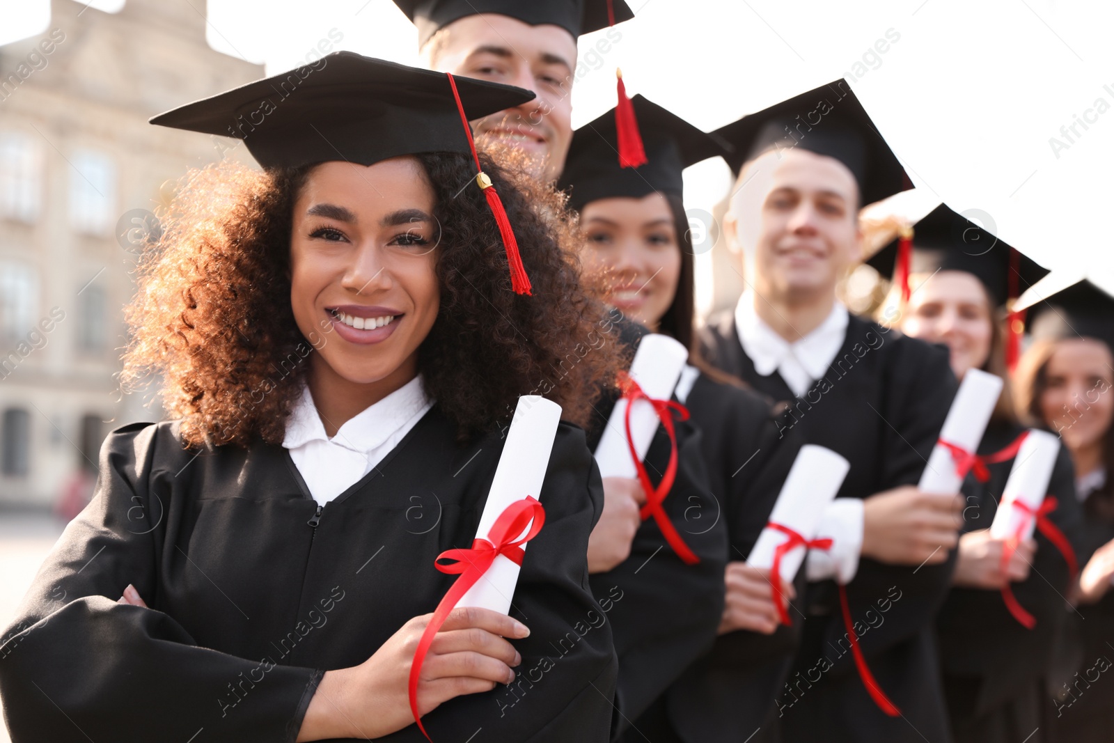 Photo of Happy students with diplomas outdoors. Graduation ceremony