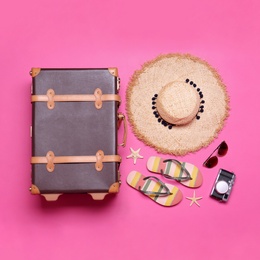 Photo of Vintage suitcase and beach objects on pink background, flat lay
