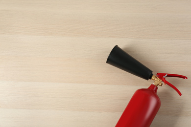 Photo of Fire extinguisher on wooden background, top view. Space for text