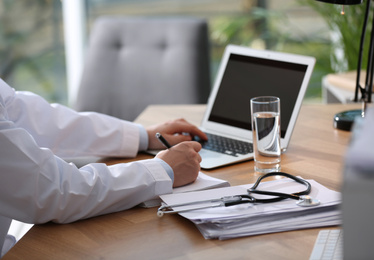 Professional doctor working on laptop in office, closeup