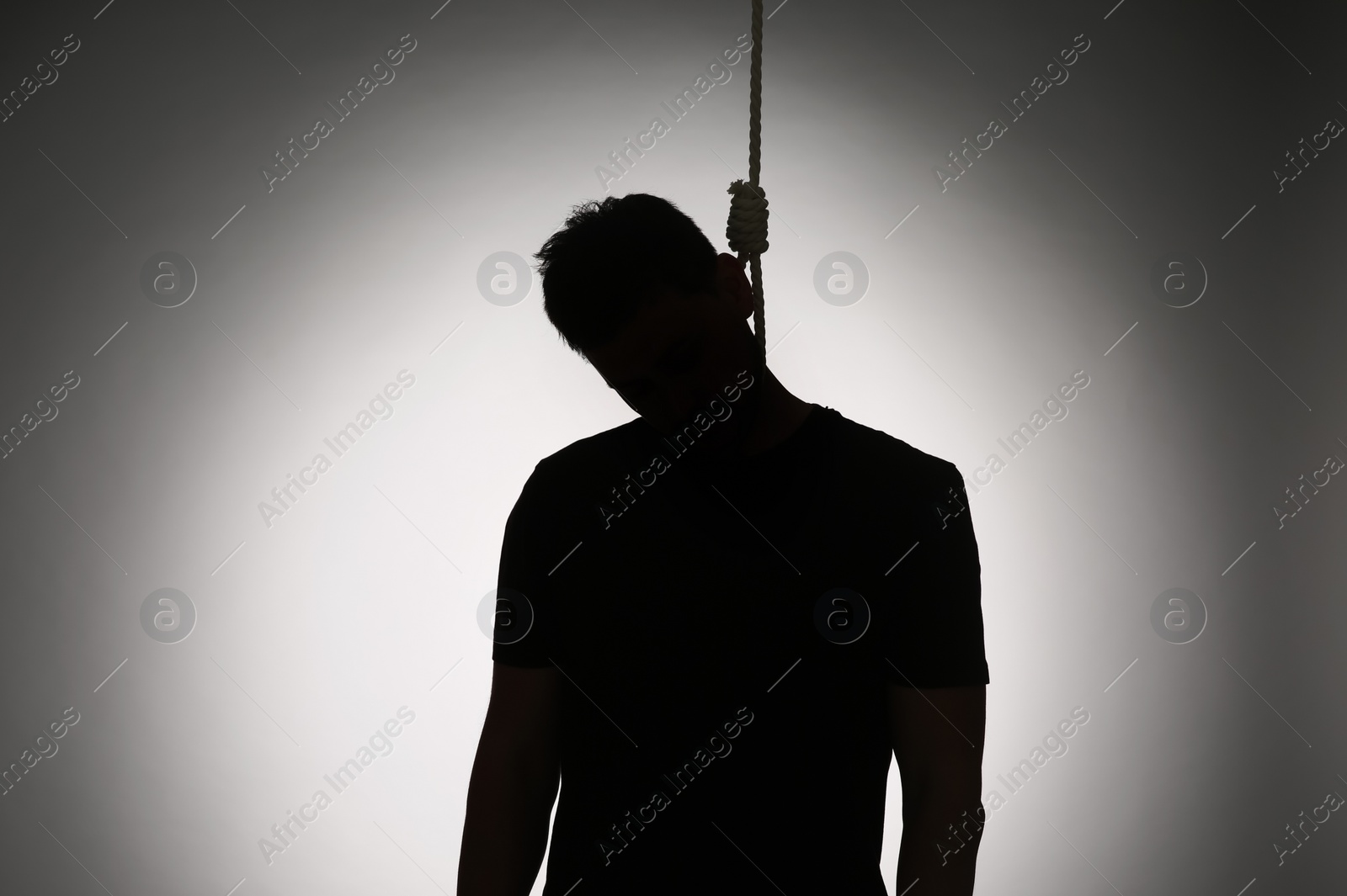 Photo of Silhouette of man with rope noose on neck against light background
