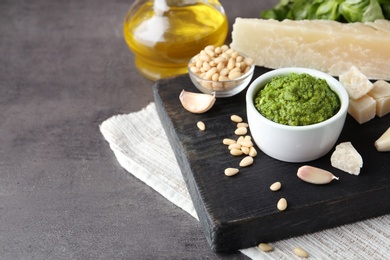 Board with bowl of pesto sauce and ingredients on table. Space for text