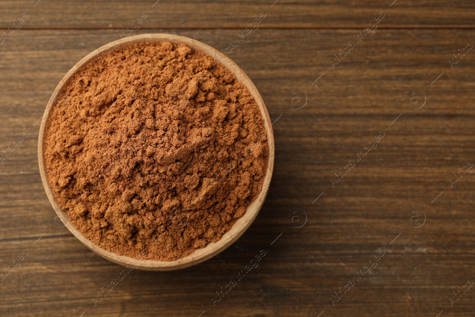 Photo of Aromatic cinnamon powder on wooden table, top view. Space for text