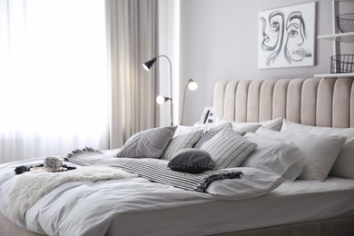 Photo of Cozy bedroom interior with cushions and striped blanket
