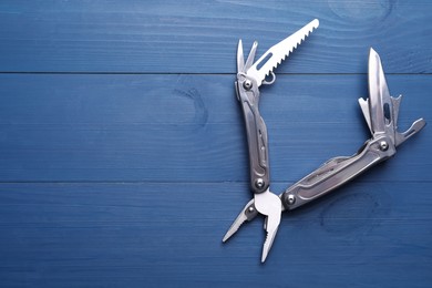 Photo of Modern compact portable multitool on blue wooden table, top view. Space for text